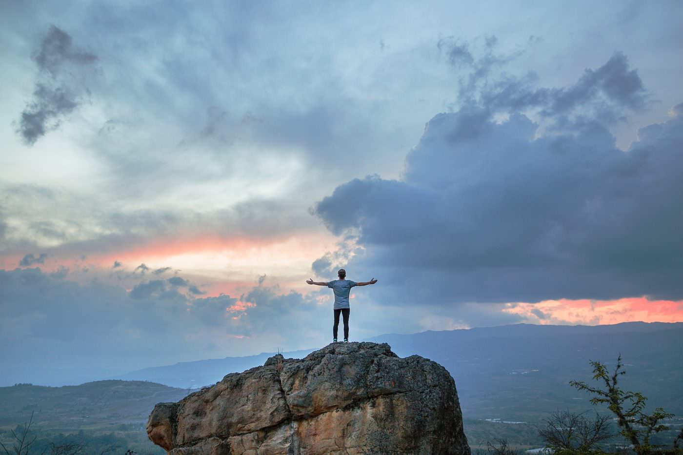 Man on rock with arms outstretched